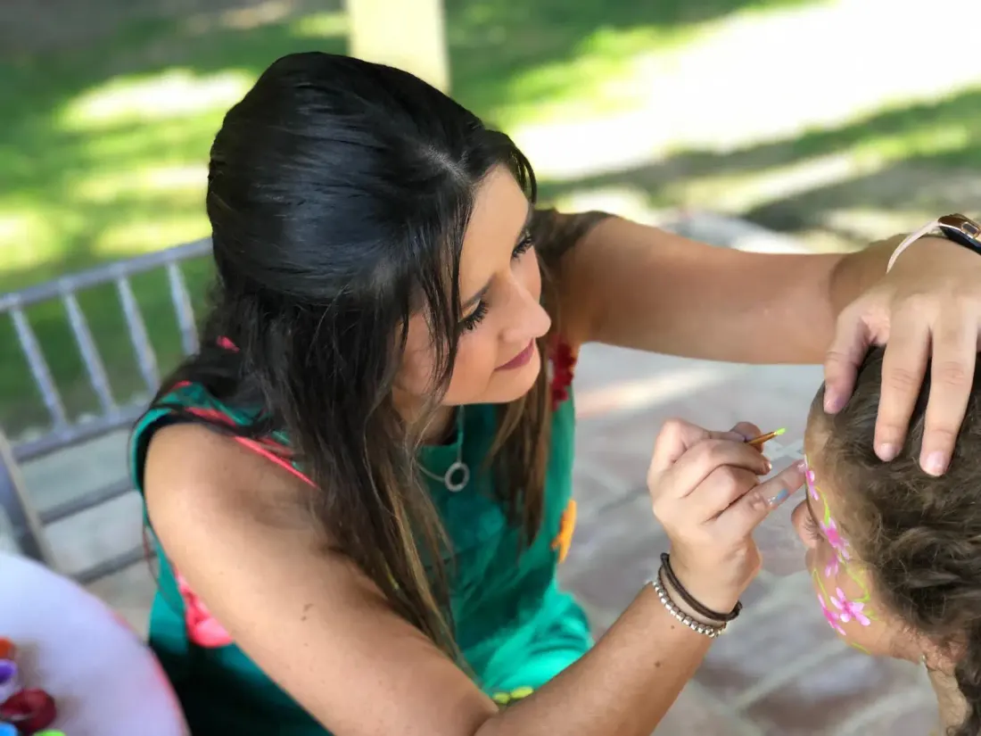 Animadora haciendo pintacaras a una niña en una fiesta al aire libre en Málaga
